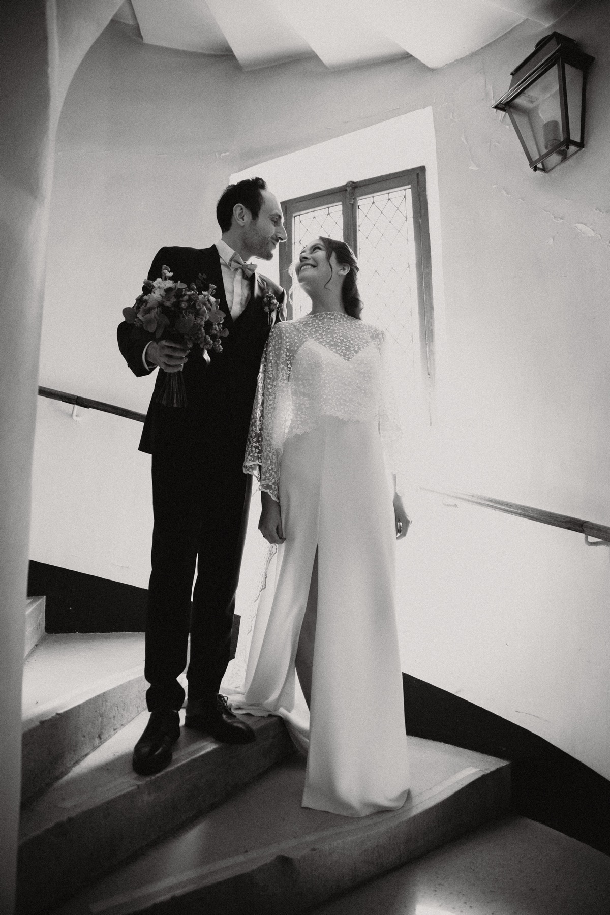 Couple de mariés en noir et blanc dans un escalier